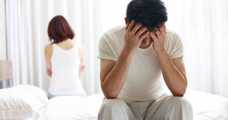 Phụ nữ ngồi trên giường nhìn xa xăm